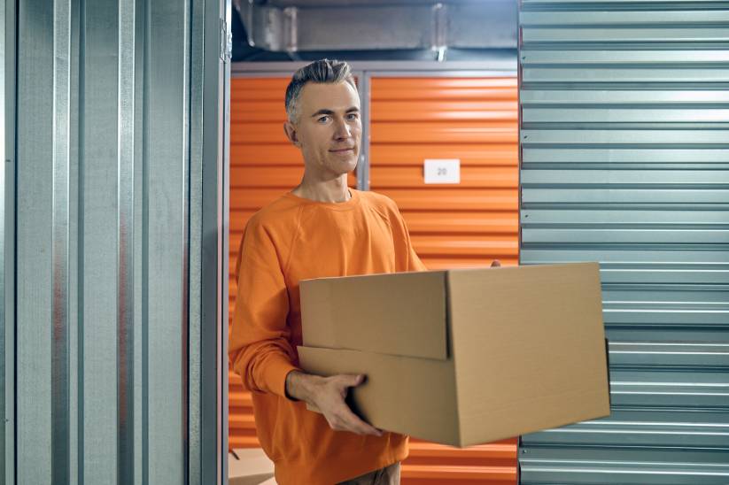 homem vestido de laranja segurando uma caixa