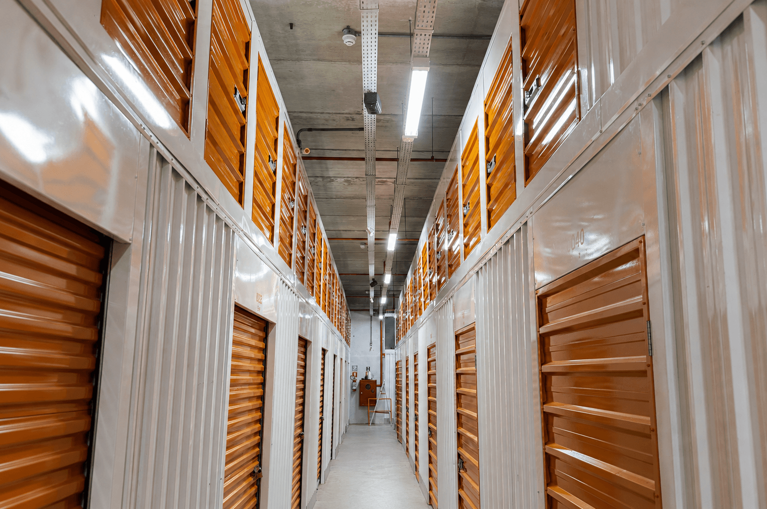 Foto real dos novos boxes compactos da Estoque Tudo, mostrando a estrutura externa, as portas e a proporção do espaço.